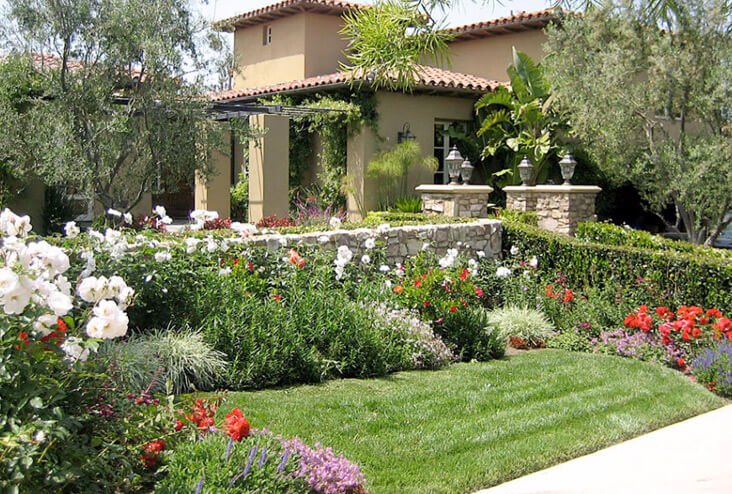 A garden with flowers and grass in front of a house.